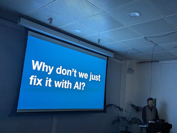 Andrew presenting a slide reading: Why don't we just fix it with AI?